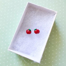 Load image into Gallery viewer, A pair of miniature apple earrings inside a white paper jewelry box
