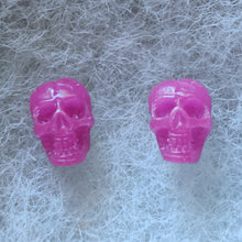 Load image into Gallery viewer, Pink skull shaped stud earrings that shimmer purple in the light. 

