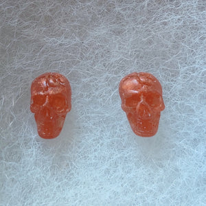 Skull stud earrings in a translucent copper color. 