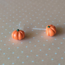 Load image into Gallery viewer, A pair of flat backed, side view, orange pumpkin earrings sitting on pastel orange and white polka dot paper.
