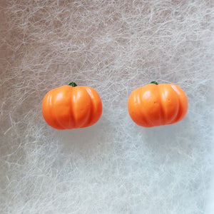 Close up view of pair of flat backed, side view, orange pumpkin earrings.