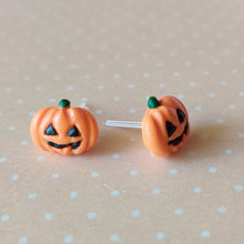 Load image into Gallery viewer, A pair of flat backed jack o&#39; lantern earrings with relief sculpted detail and painted on face and stem. The earrings are sitting on a orange and white polka dot background. 
