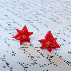 A close up of a pair of red poinsettia earrings.