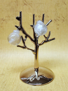 Two miniature Christmas ornament baubles in a clear color with silvery white swirls inside. The earrings are shown before being attached to hooks, and are hanging on a small, silver, leafless tree stand. 