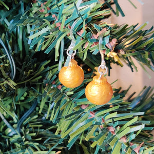 One pair of miniature gold baubles with a reflective textured surface. The earrings are shown hanging from an artificial Christmas tree branch.