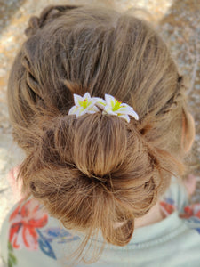 Two lily spin pins added to the top of a bun for decoration. The hairstyle is shown on a child for size reference. 