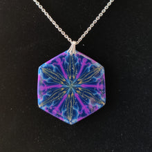 Load image into Gallery viewer, A large hexagonal pendant hanging from a silver colored chain and bail. The pendent is dark blue with purple, gold, and light blue colors radiating out from the center. It is displayed with a black velvet background. 
