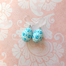 Load image into Gallery viewer, Patterned Easter egg shaped dangle earrings in a blue and white one a pink paper background.
