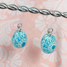 Load image into Gallery viewer, Patterned Easter egg shaped dangle earrings in a blue and white color hanging from a silver wire. 
